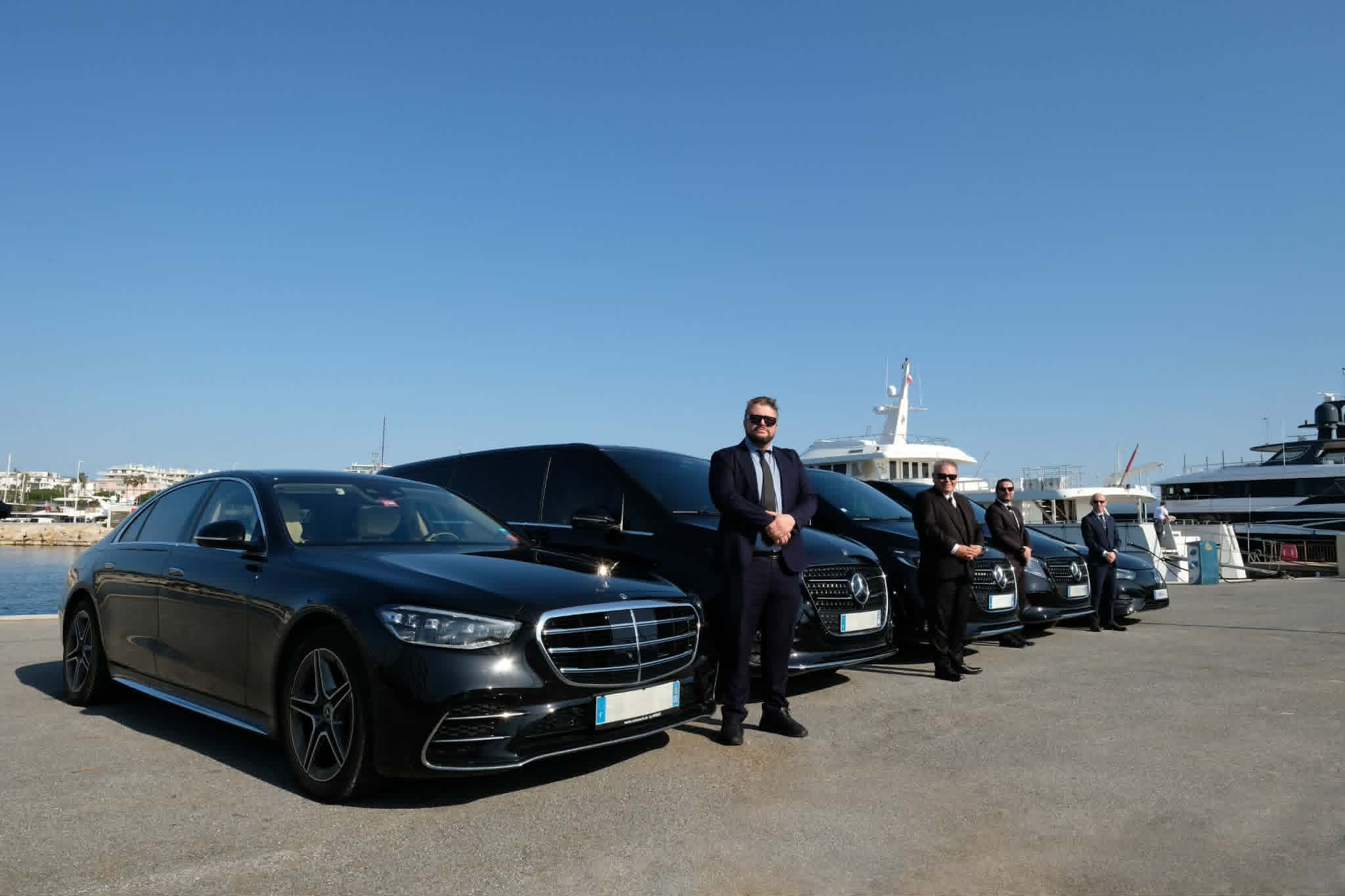 Golden Riviera Limo chauffeurs standing beside luxury Mercedes vehicles at a French Riviera marina